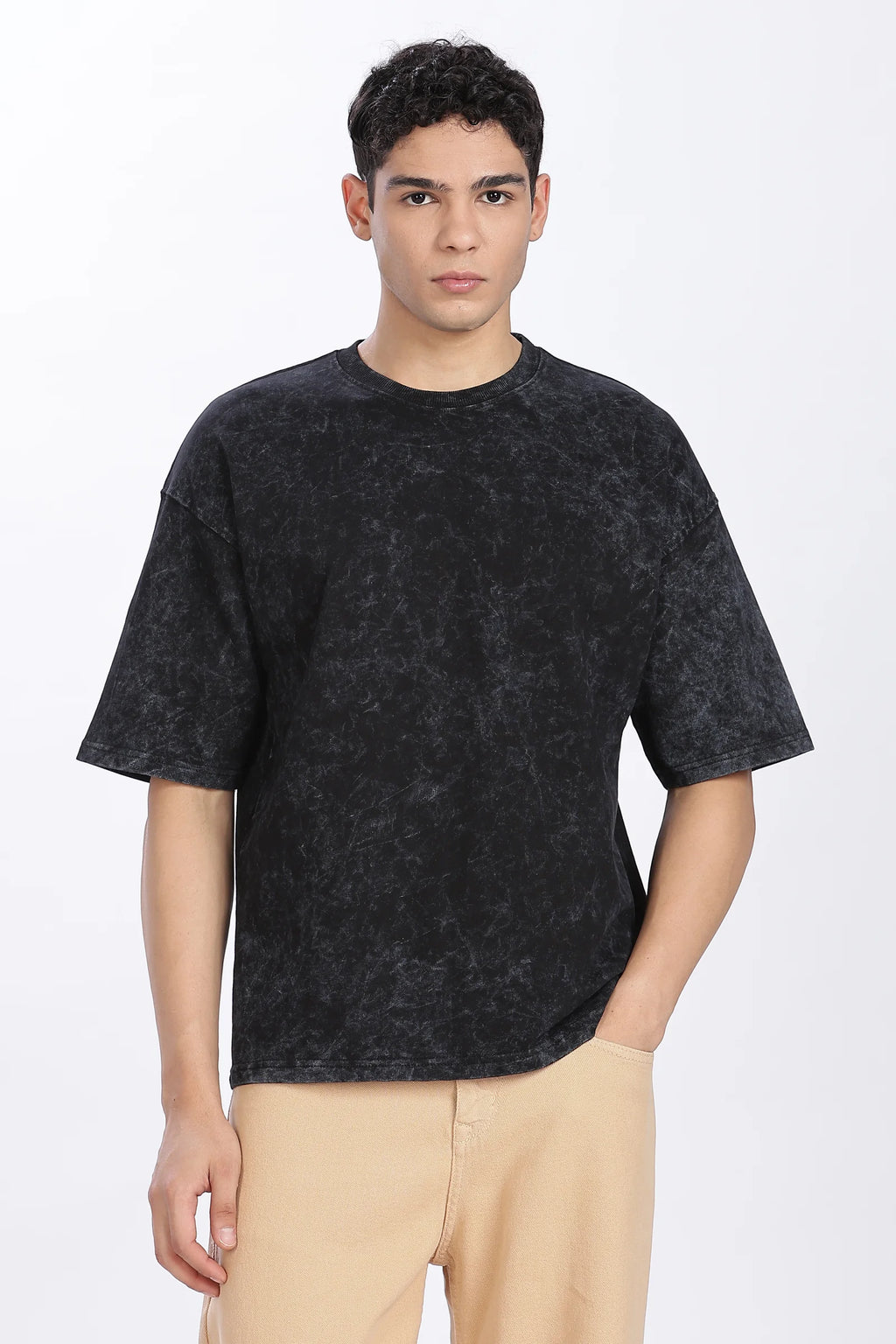 Person wearing a black t-shirt and beige pants on a white background