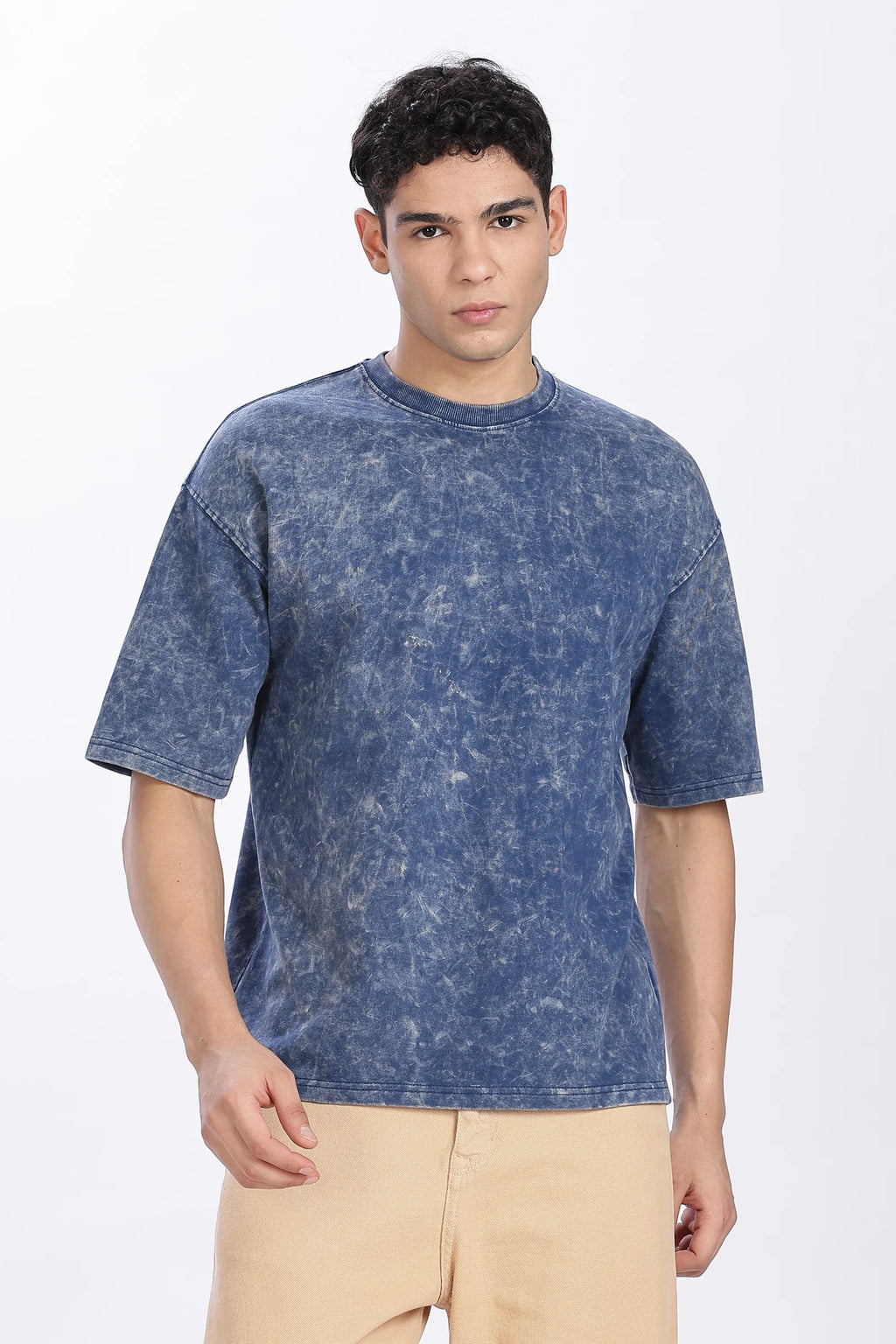 Man wearing a blue t-shirt and beige pants on a white background