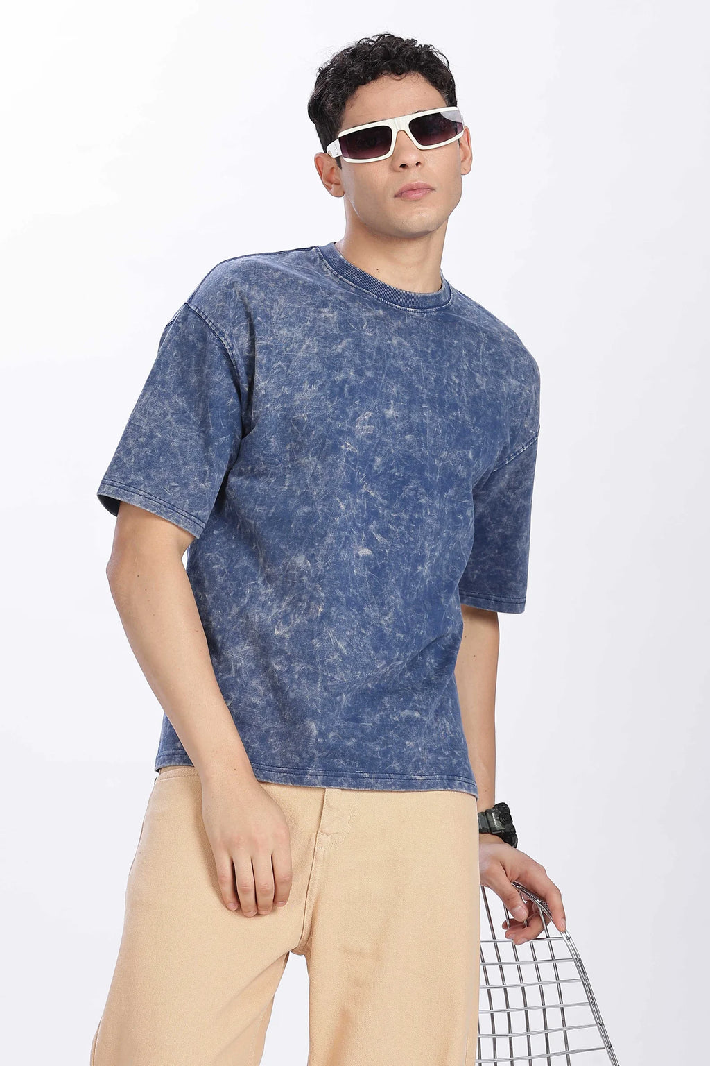 Person wearing a blue tie-dye t-shirt and beige pants on a white background