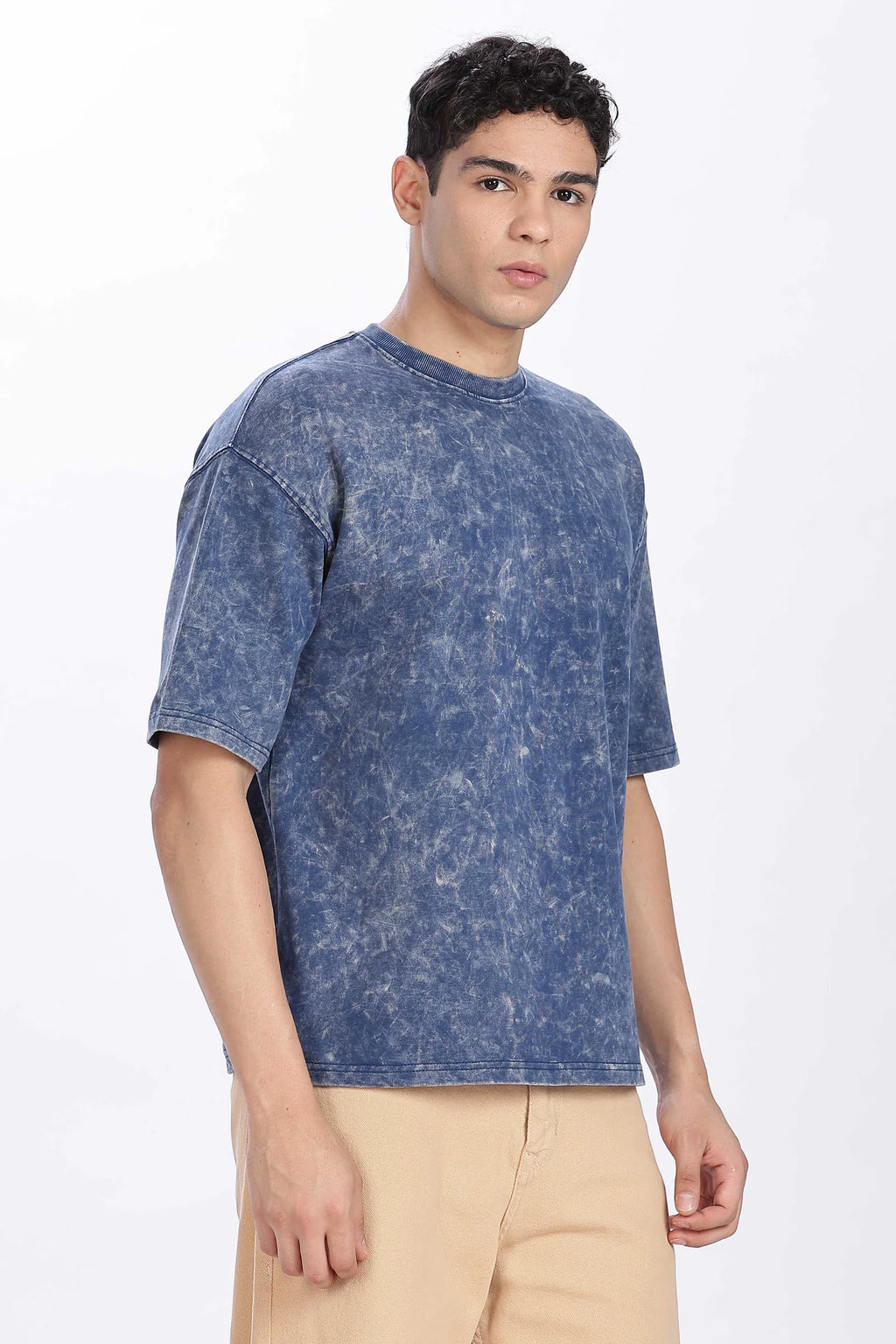 Man wearing a blue acid-wash t-shirt on a white background