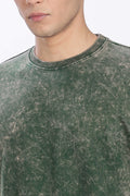 Close-up of a person wearing a green distressed sweatshirt with a blurred background