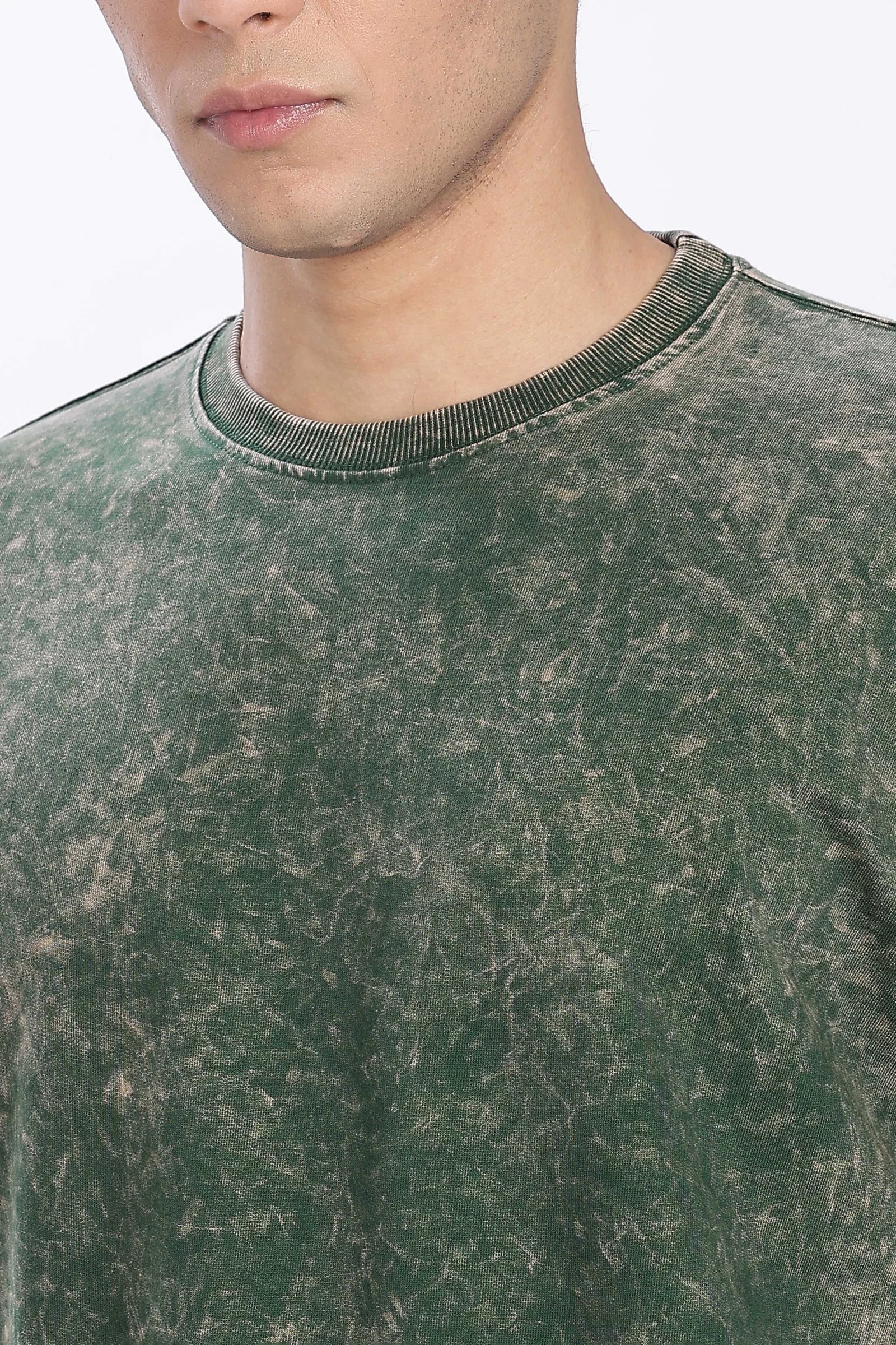 Close-up of a person wearing a green distressed sweatshirt with a blurred background