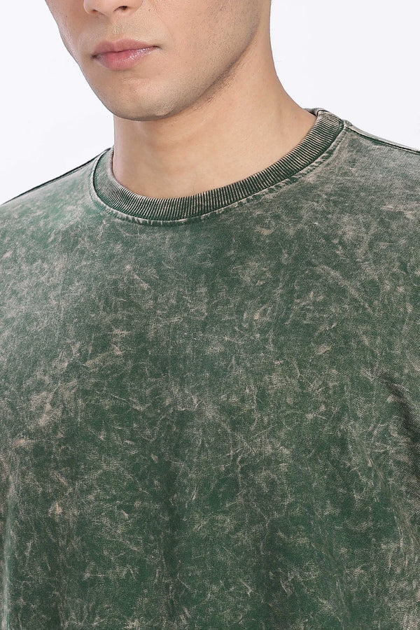 Close-up of a person wearing a green distressed sweatshirt with a blurred background