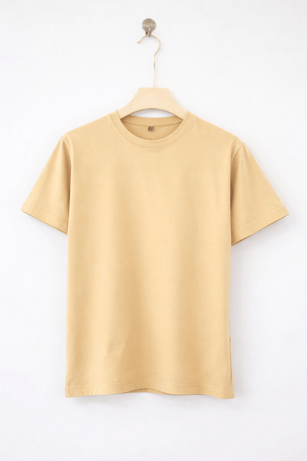 Beige t-shirt on a hanger against a white background