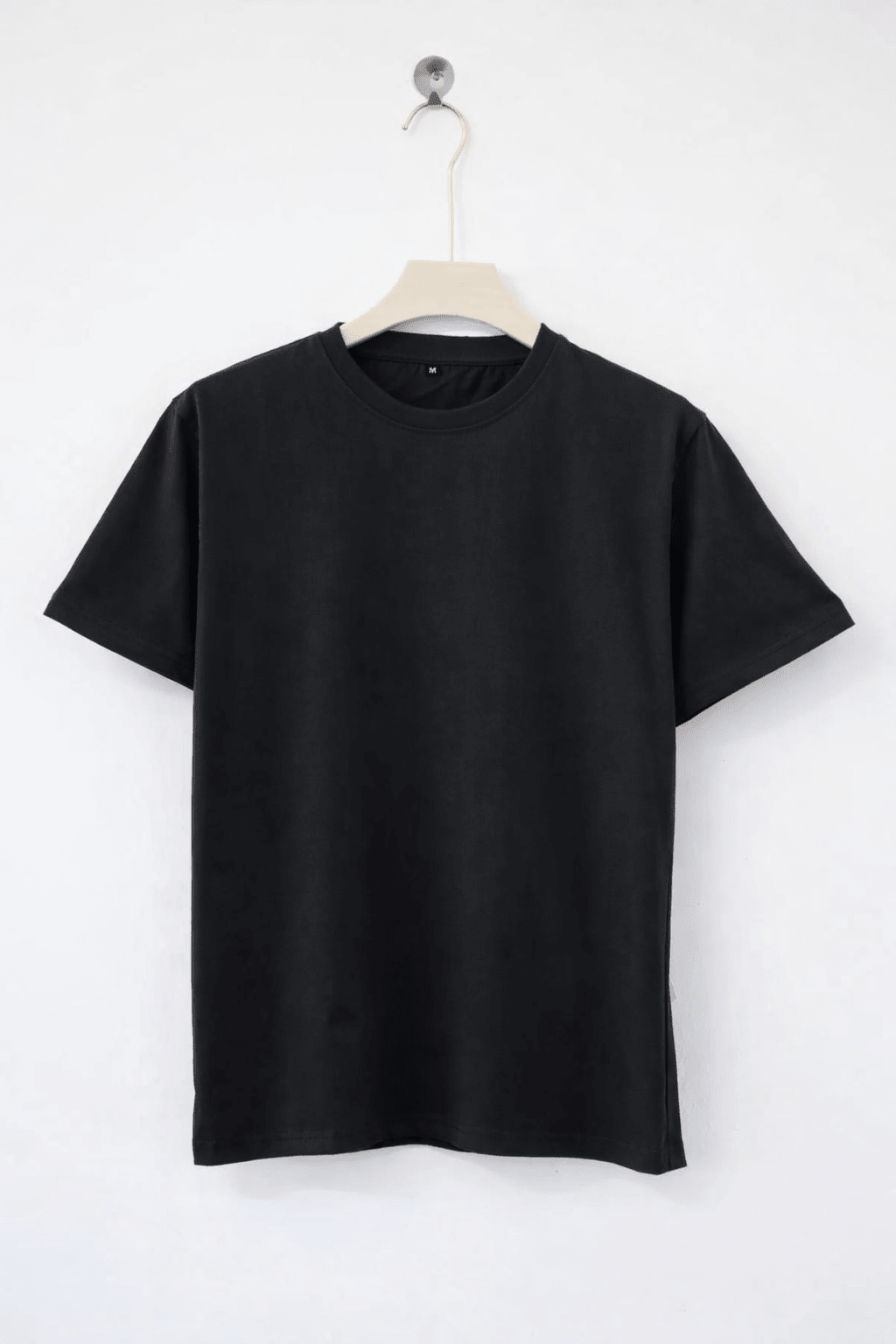 Black t-shirt on a hanger against a white background