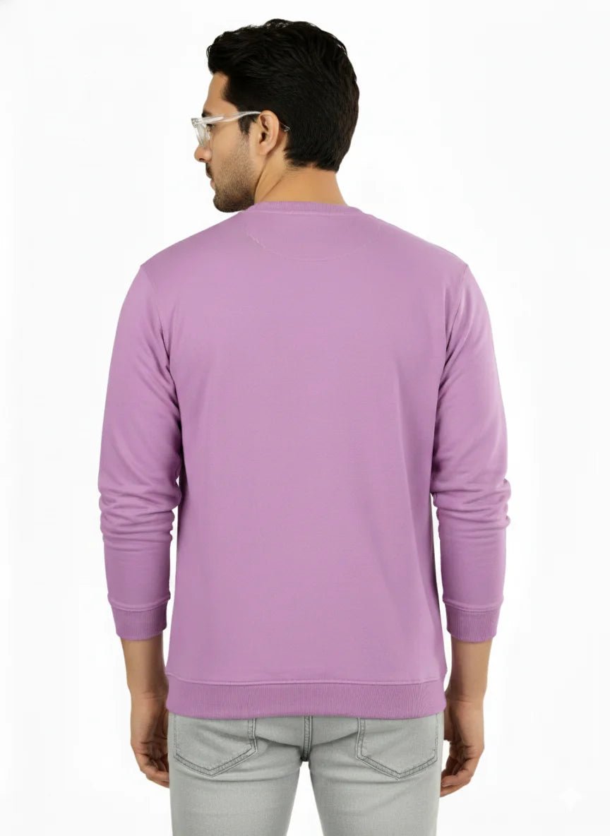 Man wearing a purple sweater and light gray pants on a white background