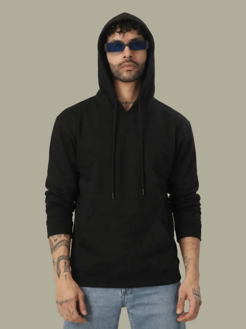 Person wearing a black hoodie and sunglasses on a plain background