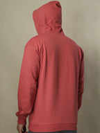 Red hoodie on a person against a beige background