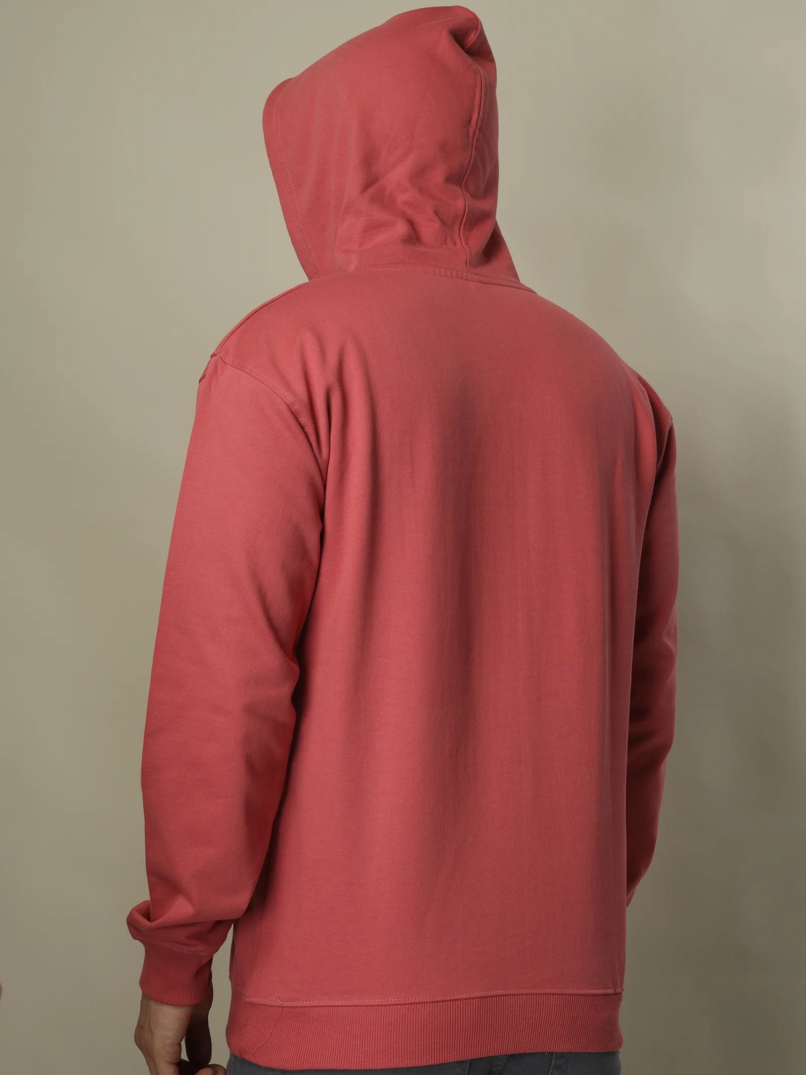 Red hoodie on a person against a beige background
