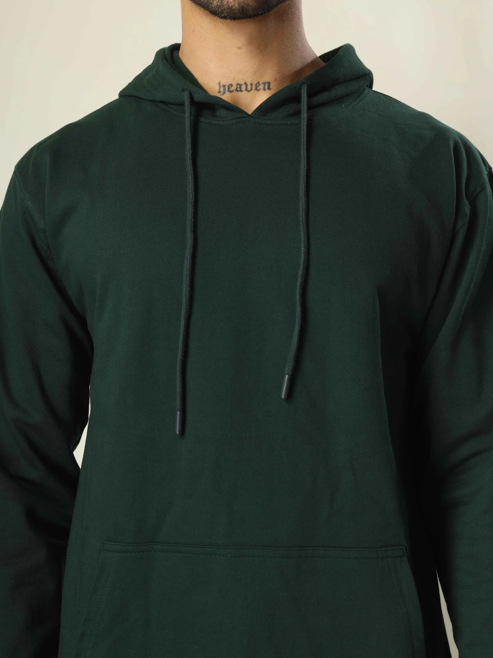 Person wearing a dark green hoodie with a neutral background