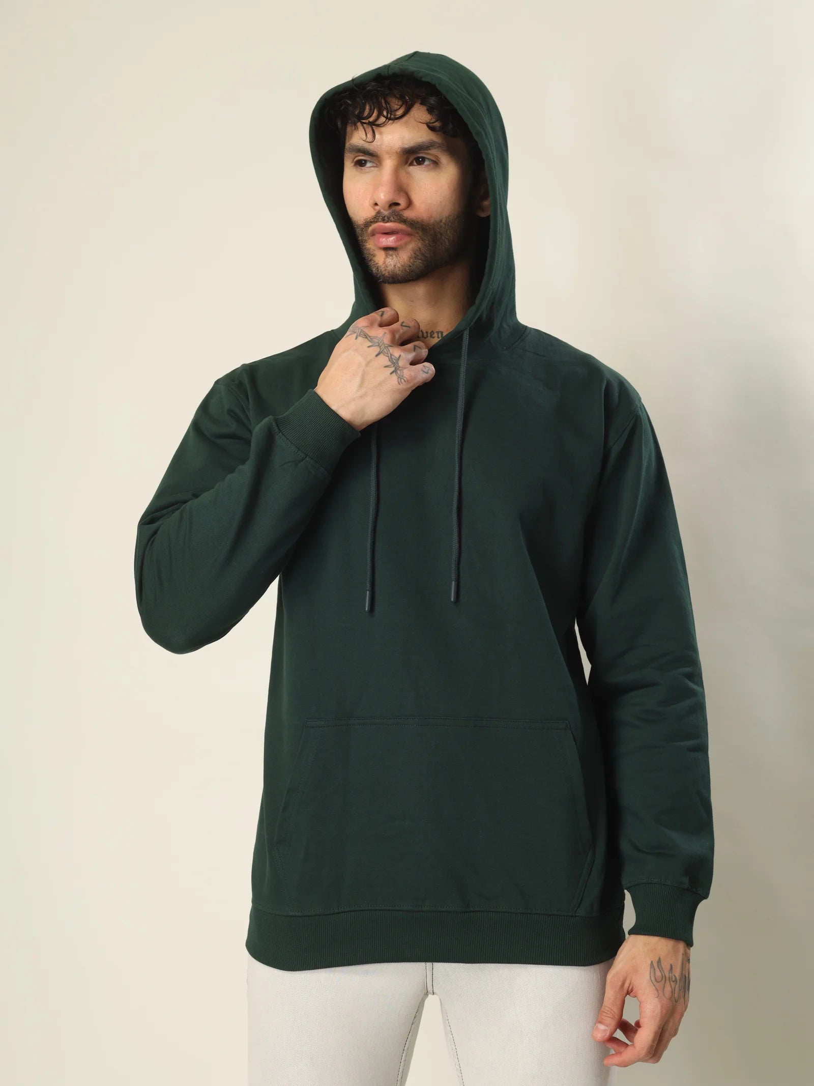 Man wearing a dark green hoodie against a plain background