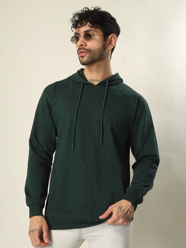 Man wearing a dark green hoodie against a plain background