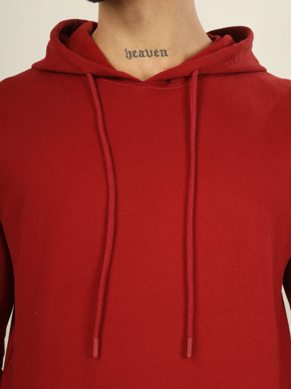 Red hoodie worn by a person with 'heaven' tattoo on neck against a neutral background