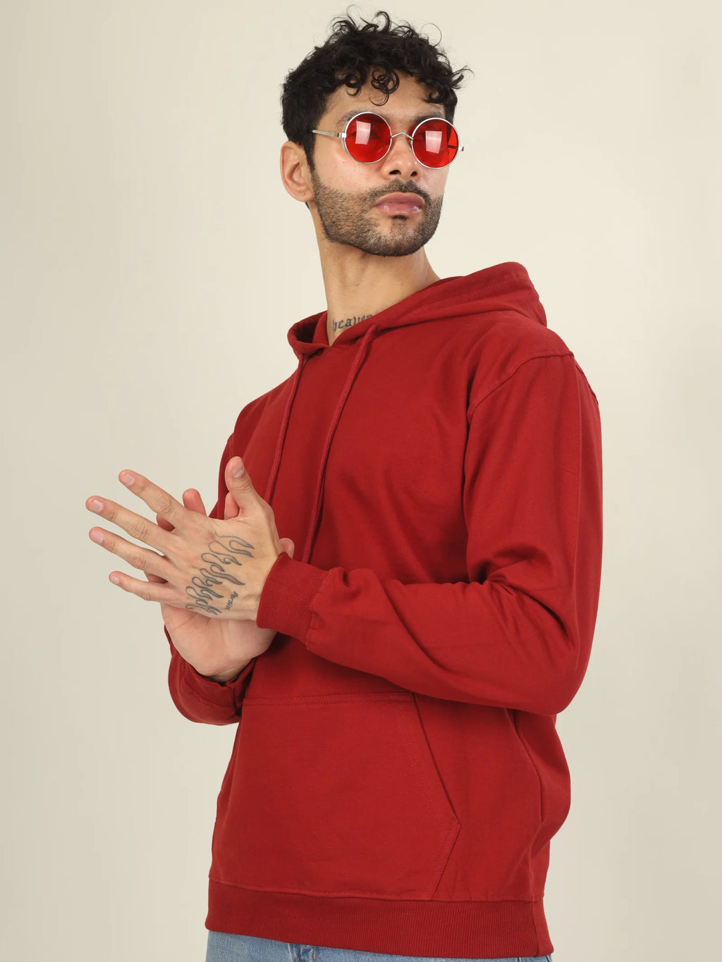 Man wearing a red hoodie and red sunglasses on a beige background