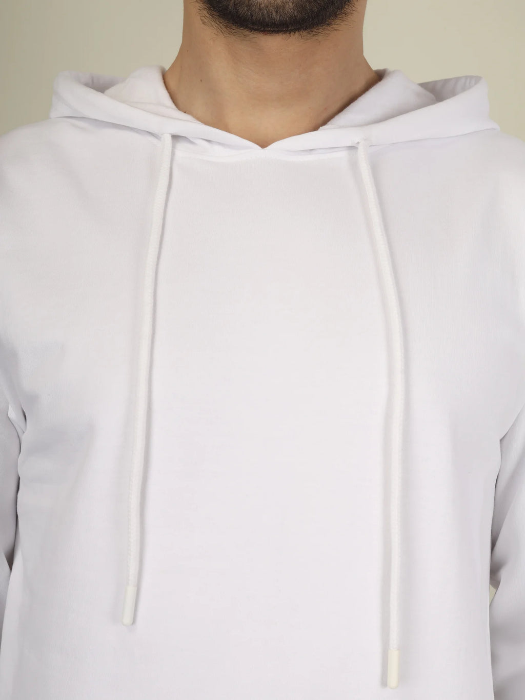 White hoodie worn by a person on a plain background