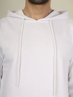 White hoodie worn by a person on a plain background