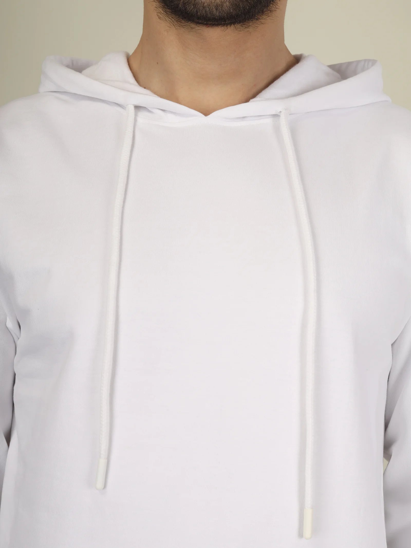 White hoodie worn by a person on a plain background