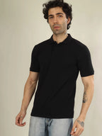 Man wearing a black polo shirt against a plain background