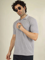 Man wearing a gray polo shirt with sunglasses on a plain background