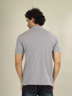 Man wearing a gray polo shirt from behind on a beige background