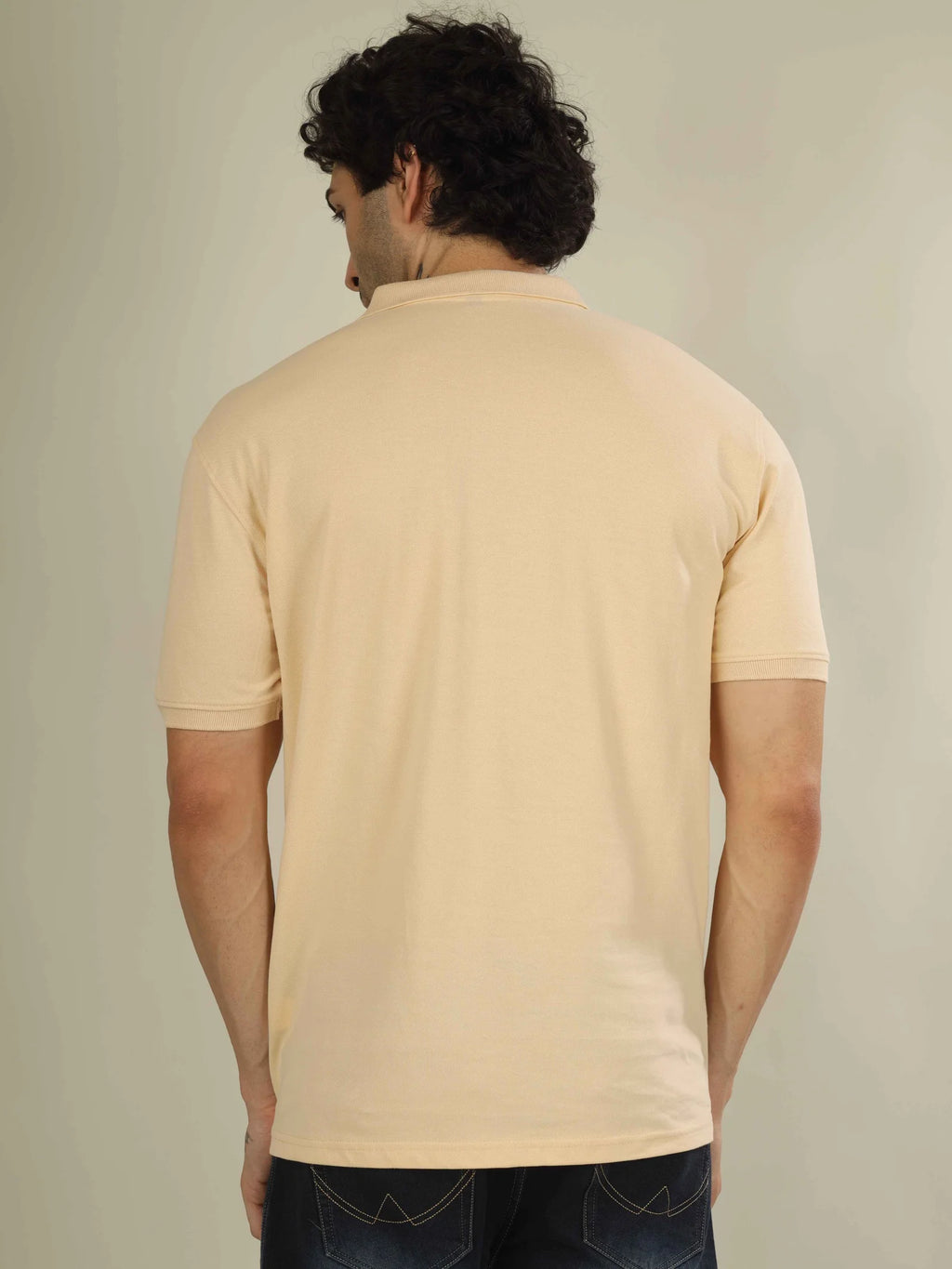 Man wearing a beige polo shirt against a plain background