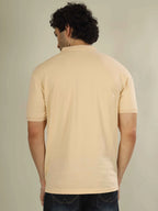 Man wearing a beige polo shirt against a plain background