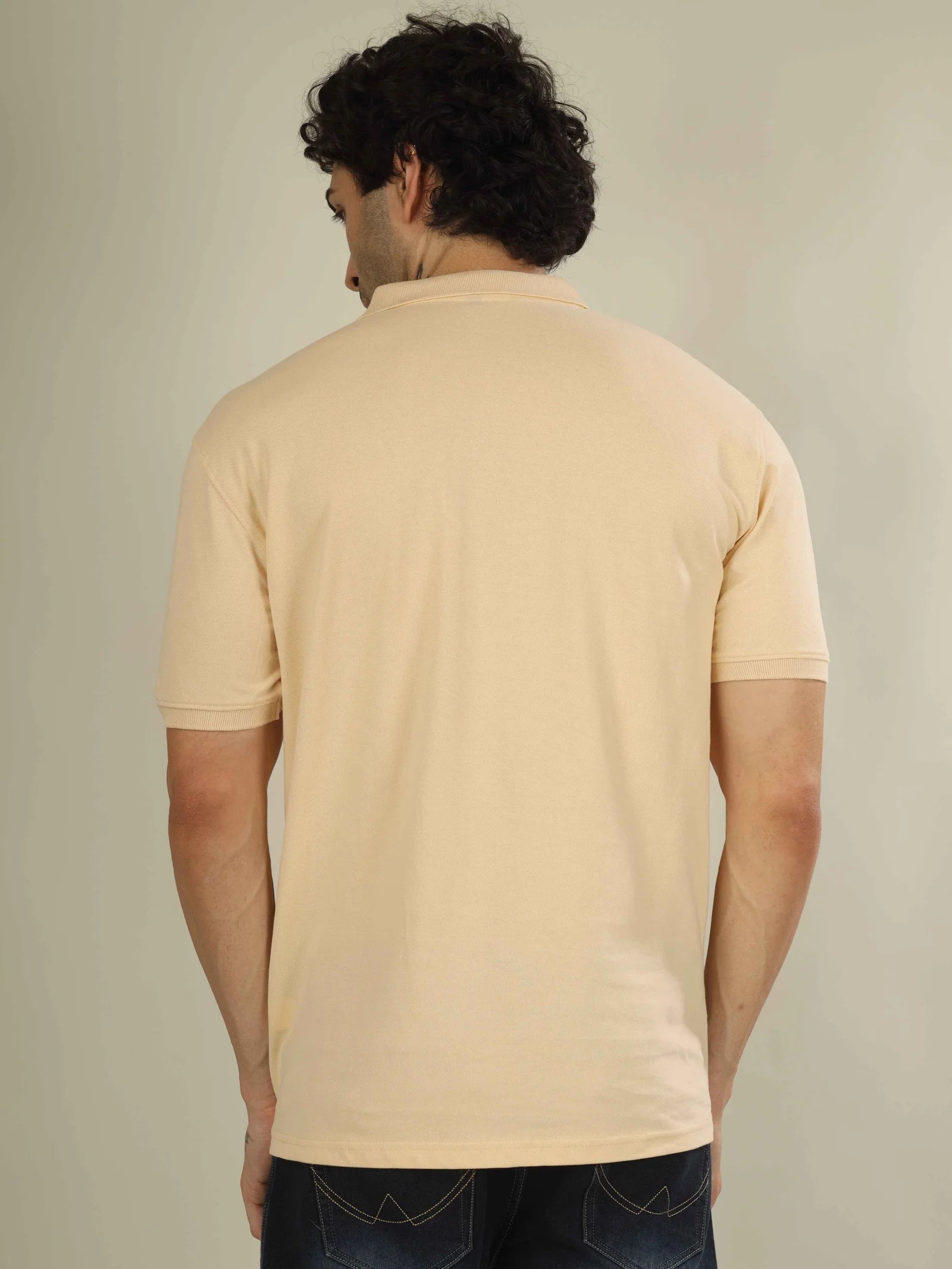 Man wearing a beige polo shirt against a plain background