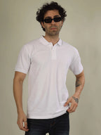 Man wearing a white polo shirt and dark sunglasses against a plain background