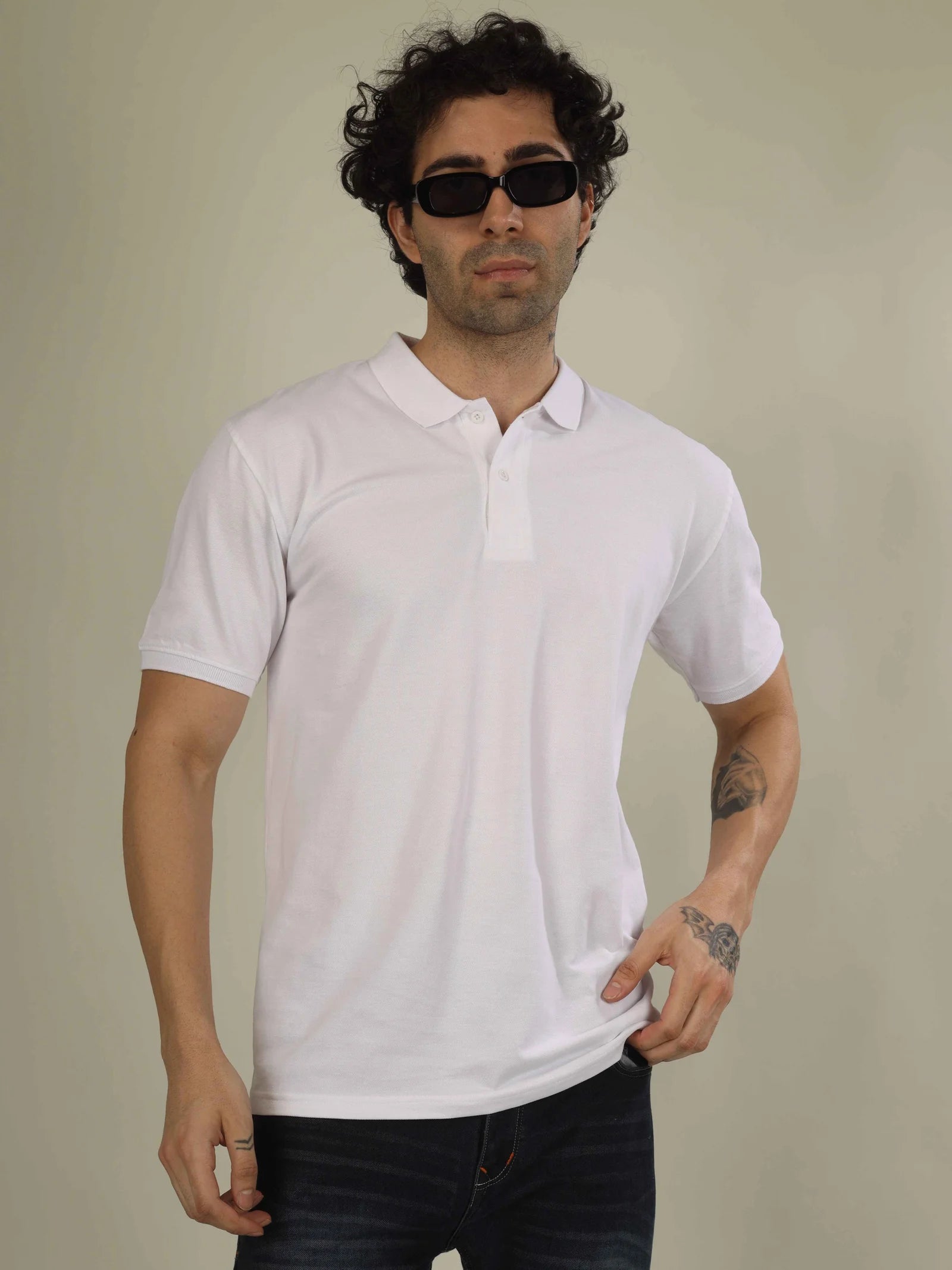 Man wearing a white polo shirt and dark sunglasses against a plain background