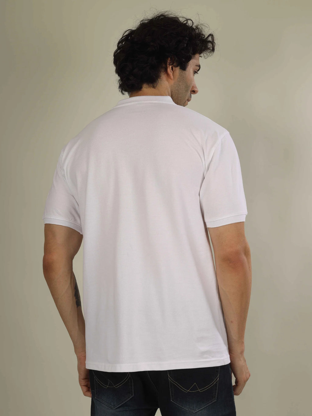 Man wearing a white polo shirt against a beige background