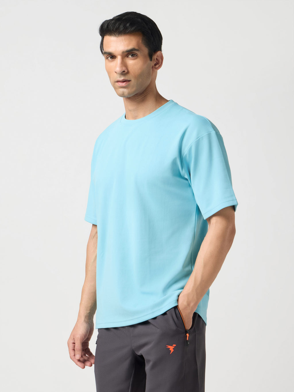 Man wearing a light blue t-shirt and gray pants on a white background