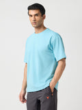 Man wearing a light blue t-shirt and gray pants on a white background