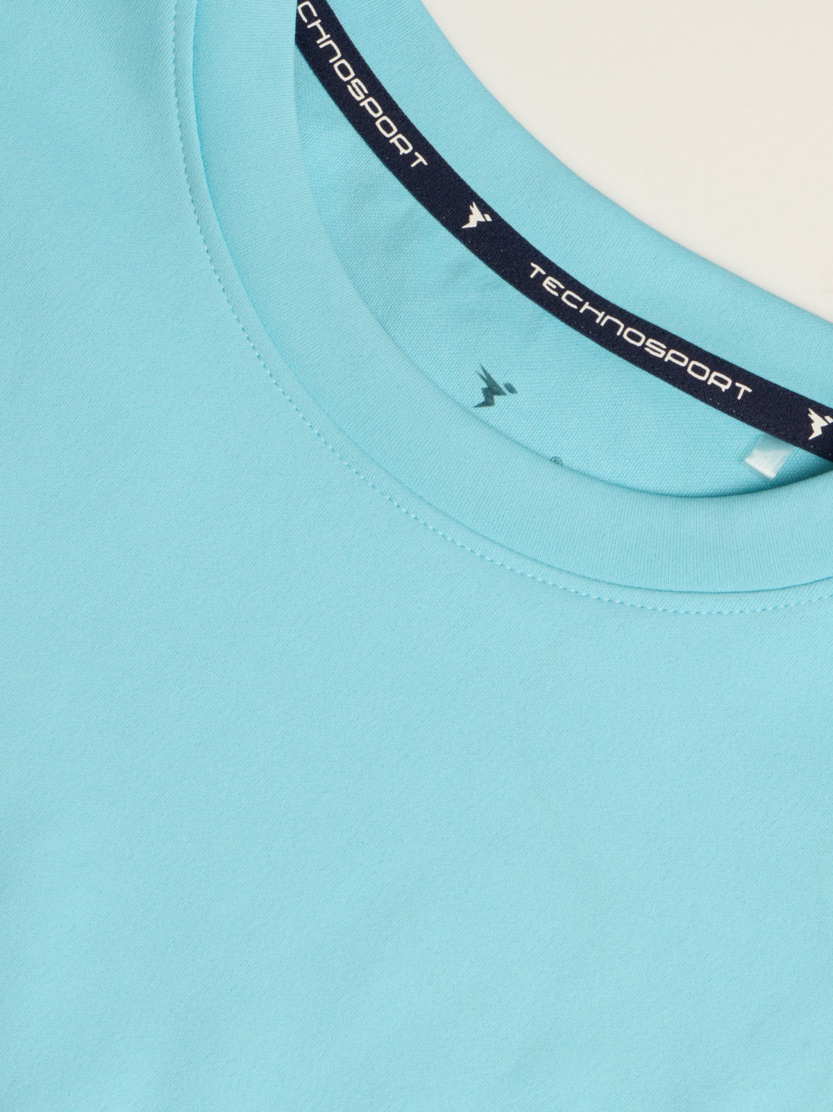 Close-up of a light blue crewneck t-shirt by Technosport, showing the inner neck label with the brand name and logo.