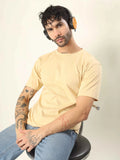 Man wearing a yellow t-shirt and headphones sitting on a chair against a plain background