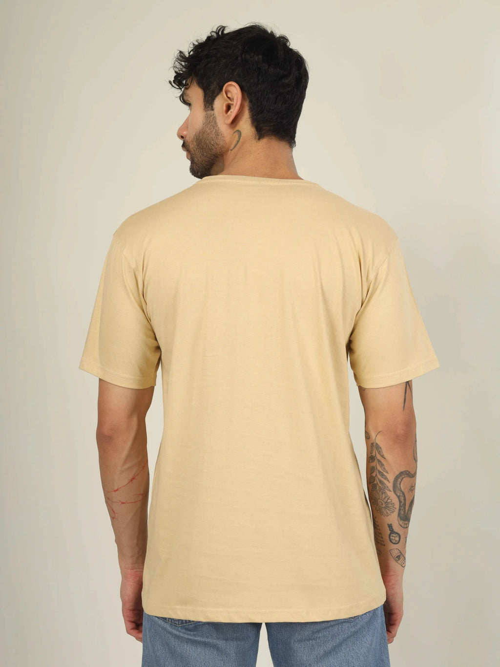 Man wearing a beige t-shirt against a plain background