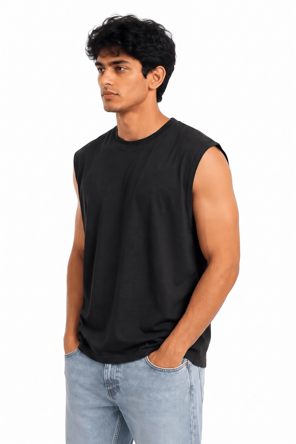 A man wearing a black sleeveless crewneck t-shirt and light wash blue jeans, standing against a solid white background.