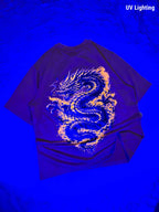 A dark purple t-shirt featuring a large, glowing yellow and blue dragon graphic on the back, displayed under UV lighting against a textured blue background.