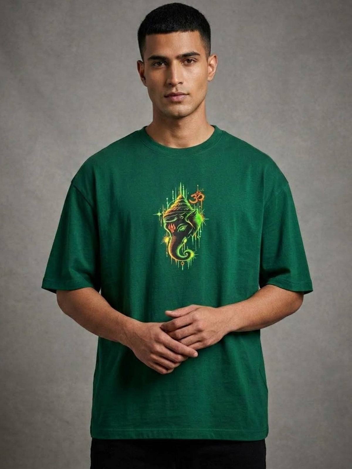 A man wearing a dark green crewneck t-shirt with a colorful seahorse graphic on the chest, standing against a textured gray studio background.