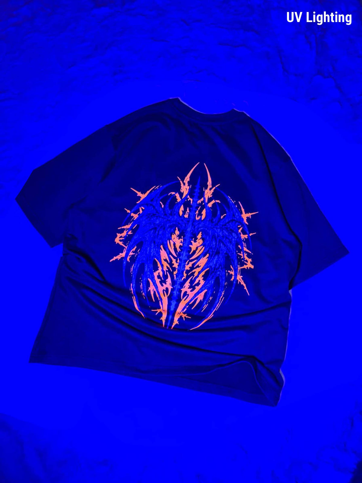 A black t-shirt displayed under UV lighting, showing a glowing neon orange and blue graphic on the front. The text 'UV Lighting' is visible in the top right corner.