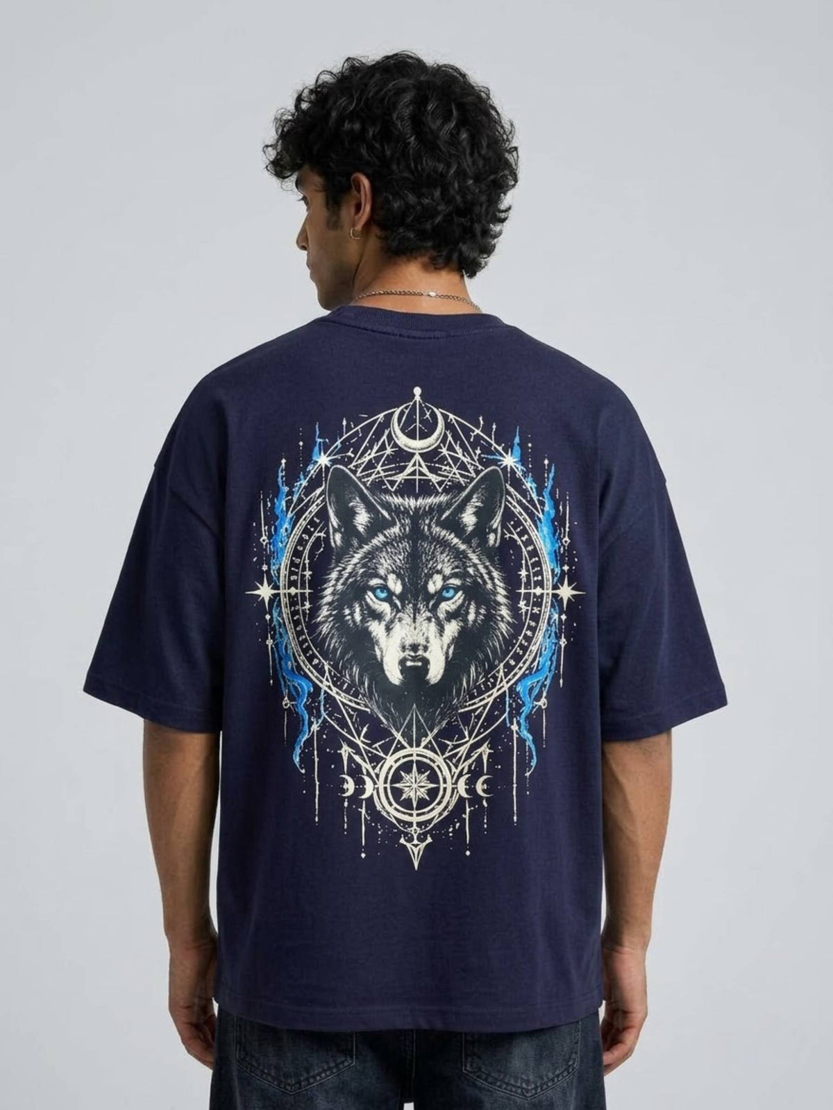 A man viewed from behind wearing a navy blue t-shirt with a large graphic print of a wolf's head inside a circular dreamcatcher design with blue and white details.