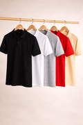 Five polo shirts in black, white, gray, red, and beige hanging on a rack against a beige background.